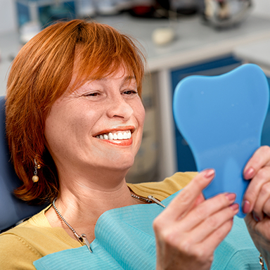Red-haired woman checking smile in mirror