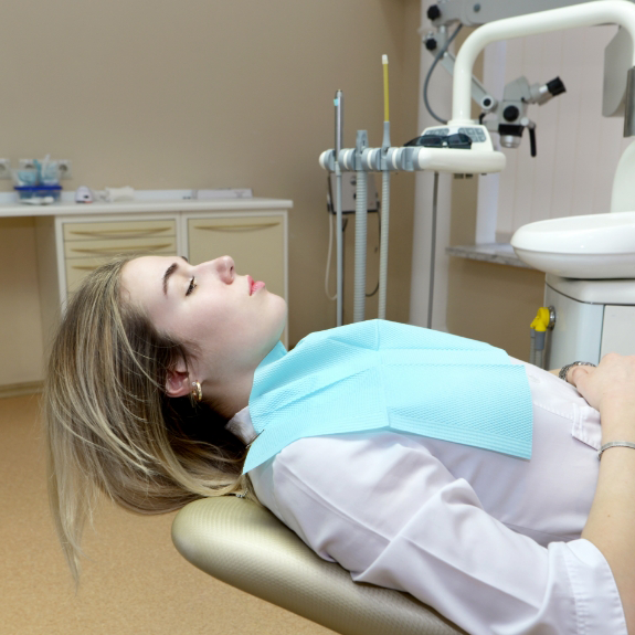 Young woman leaning back in the dental chair with her eyes closed