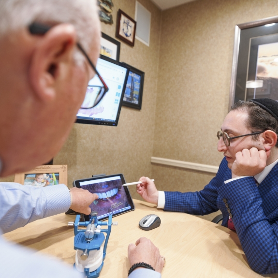 Doctor Mohr and Doctor Ariel at a desk discussing a photo of a patients teeth