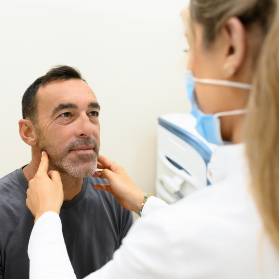 Dentist feeling the sides of a patient's jawbone