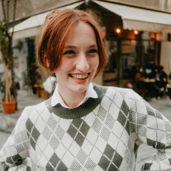 Woman in an argyle sweater smiling at an outdoor restaurant table