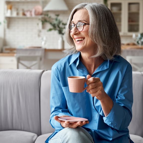 Smiling senior woman having coffee on her couch