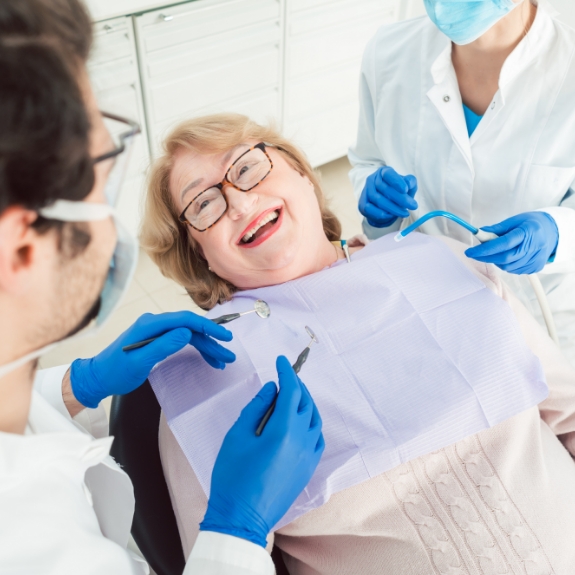 Older woman in the dental chair smiling at her dental team