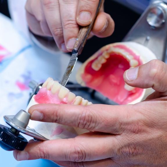 Dental lab technician adjusting a denture