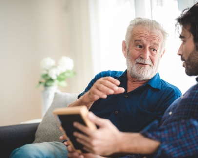 Senior man talking to the younger man on the couch next to him