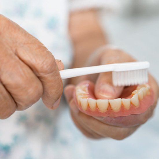 Older man brushing denture