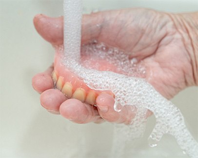 Older woman rinsing denture