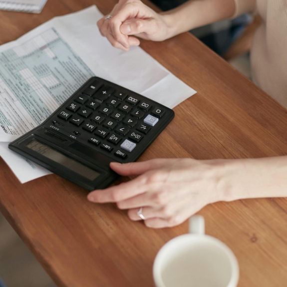 Person sitting at a desk and typing on a calculator