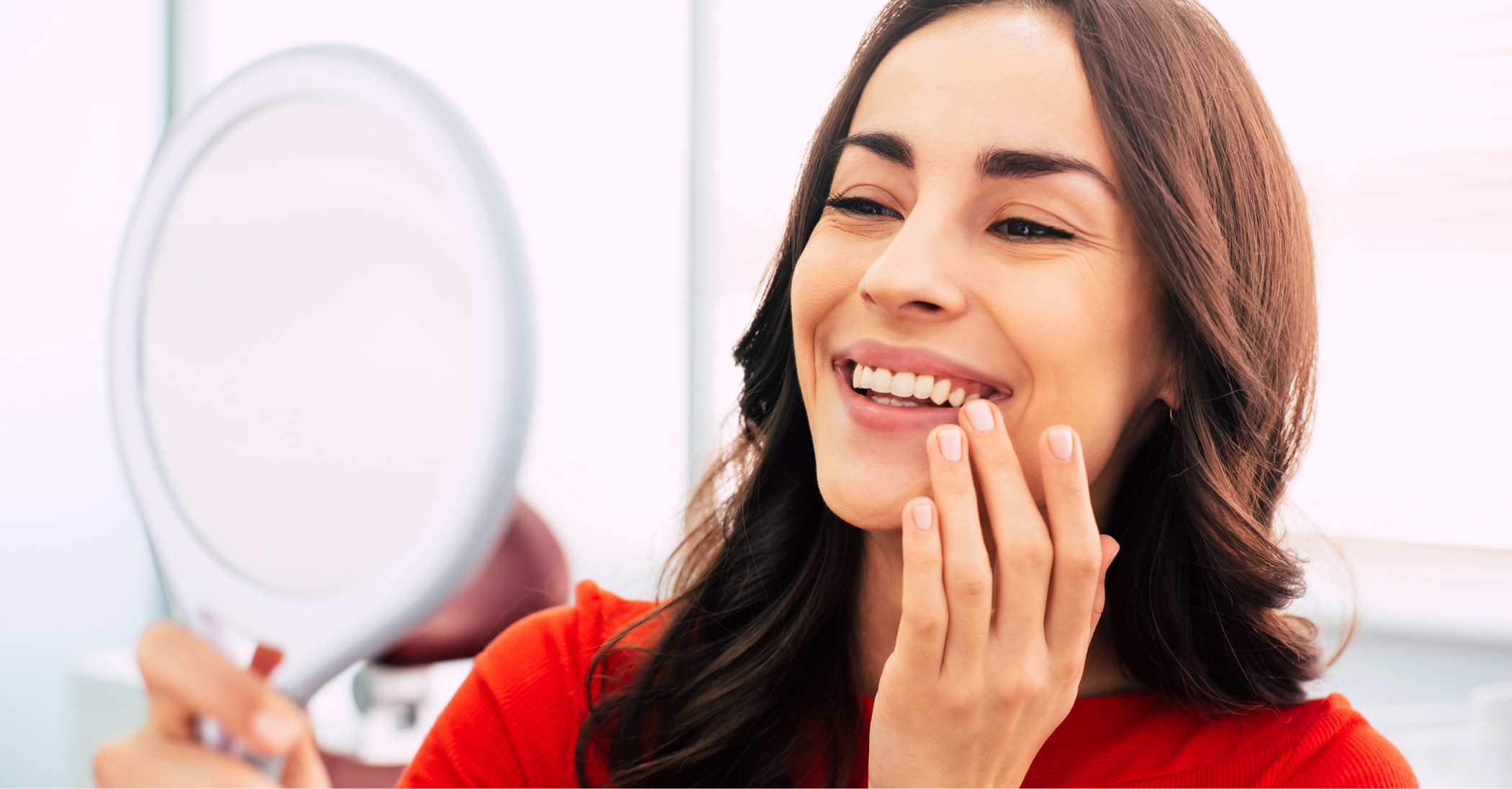 Dental patient looking at her smile in a mirror after a full mouth reconstruction in Massapequa Park