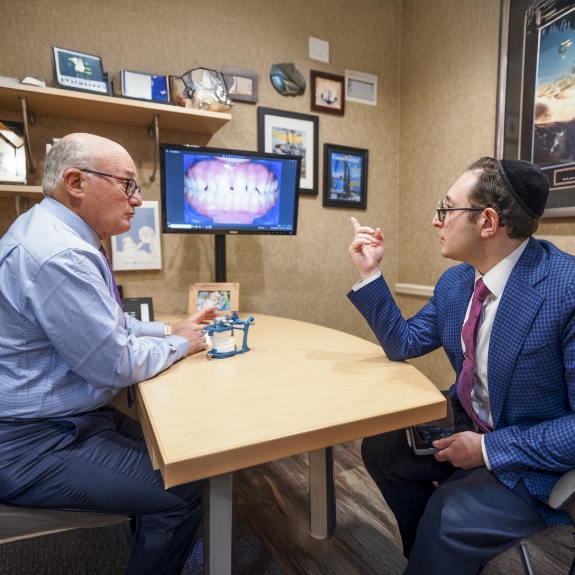 Doctor Ariel and Doctor Mohr discussing a photo of a patients teeth on a nearby monitor