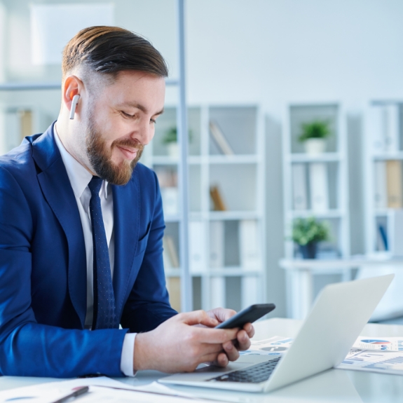 Businessman smiling while using his phone at his desk