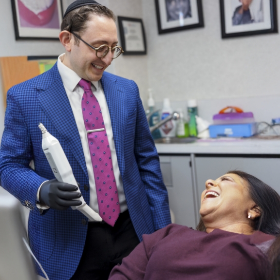 Doctor Ariel smiling at a woman in the dental chair