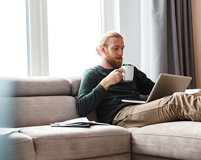 Young man sitting and working on couch
