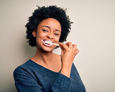 Woman brushing teeth after dental implant surgery