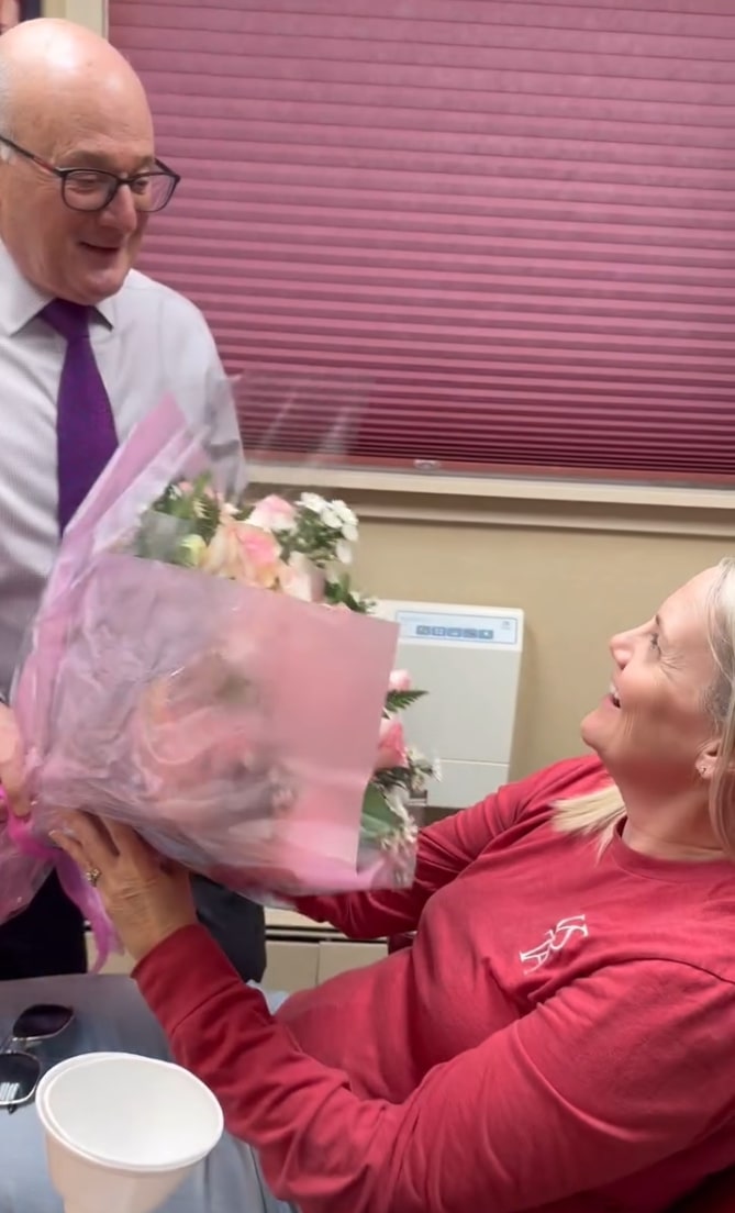 Doctor Mohr handing a flower bouquet to a woman in the dental chair