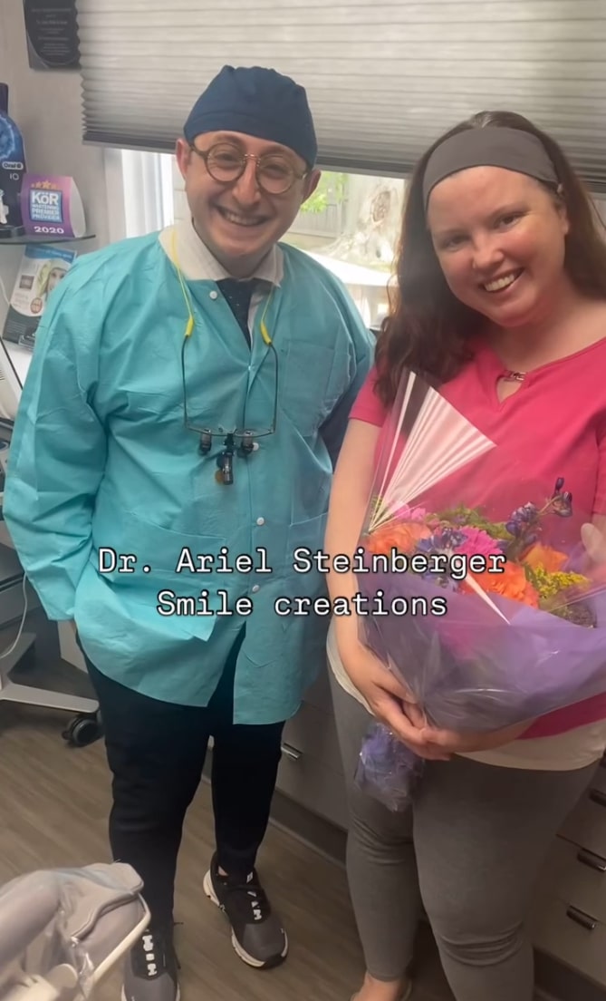 Doctor Ariel smiling with a female dental patient holding a flower bouquet