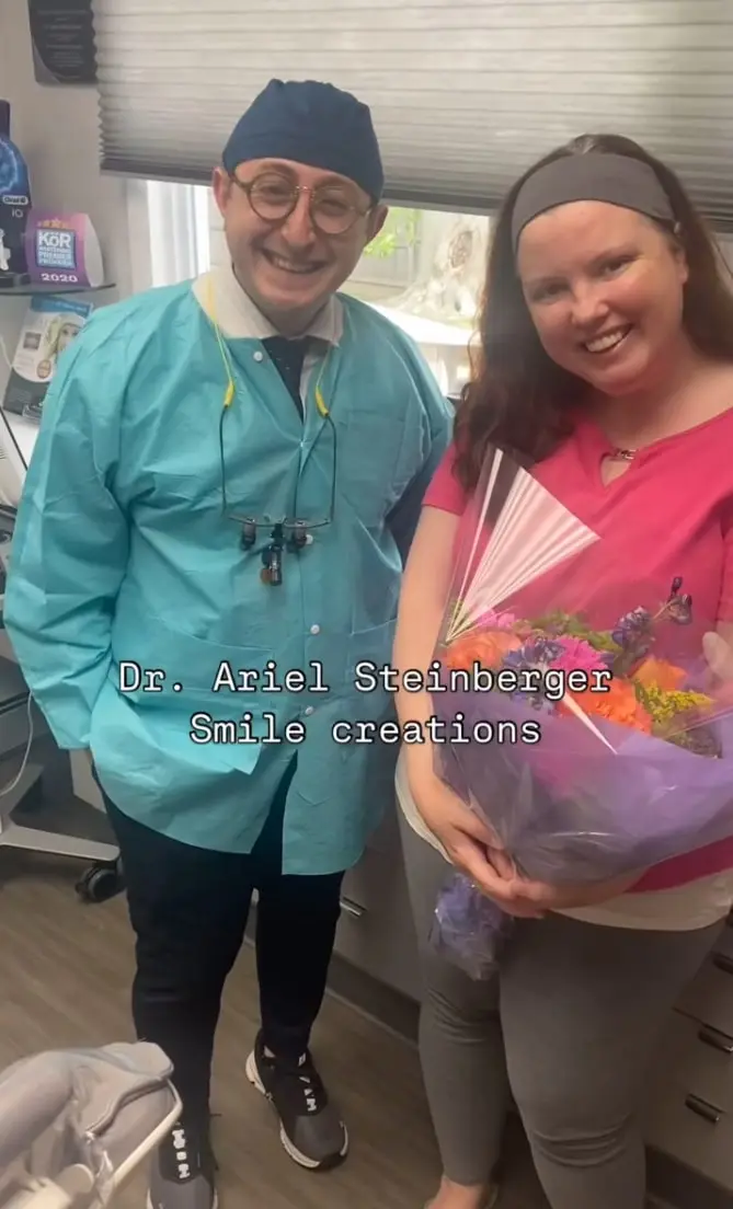 Doctor Ariel smiling with a female dental patient holding a flower bouquet