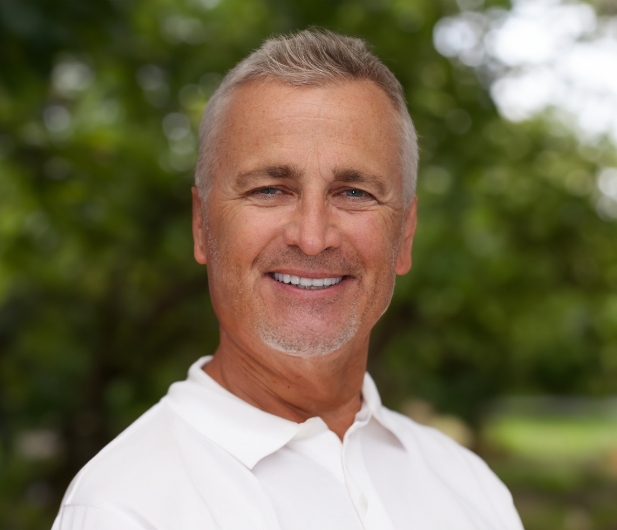 Man in a white collared shirt smiling with white teeth