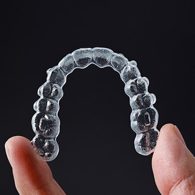 hand holding up Invisalign tray