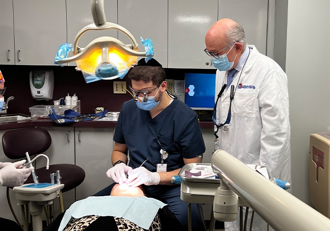 Slightly different shot of Dr. Mohr standing nearby while team member treats patient