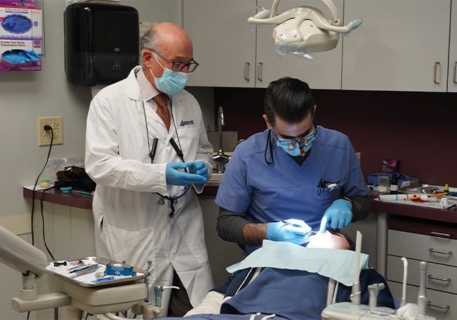 Dental team member treating patient with Dr. Mohr looking on