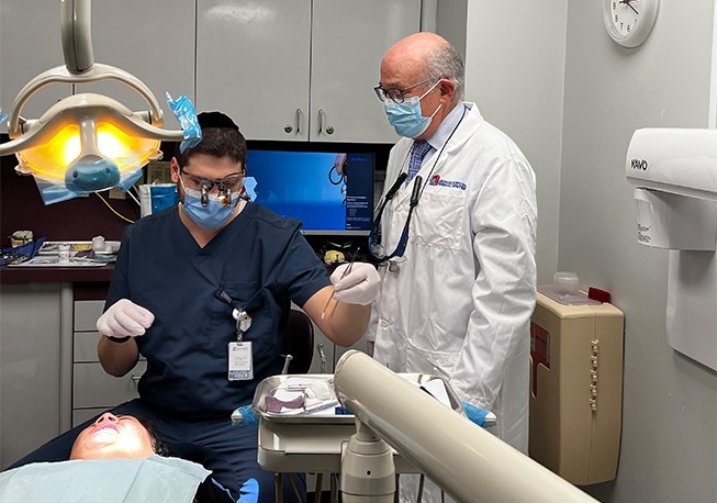 Dr. Mohr watching while student picks up dental instrument