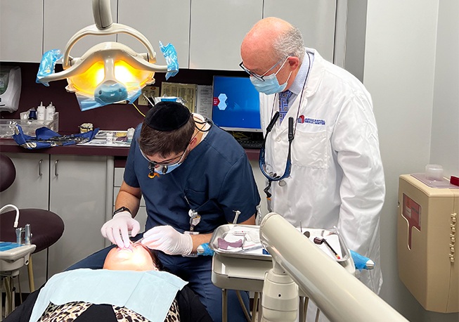 Team member treating patient while Dr. Mohr watches
