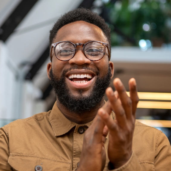 Smiling man in glasses and a light brown button down shirt