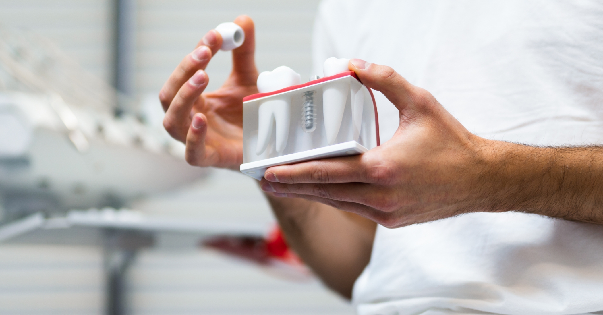 Dentist showing a patient a model of a single tooth dental implant in Massapequa Park