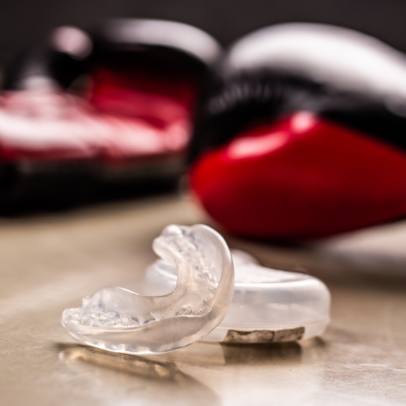 Two clear mouthguards laying next to two red boxing gloves