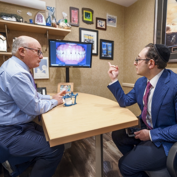 Doctor Mohr and Doctor Ariel at a desk discussing a photo of a patients teeth