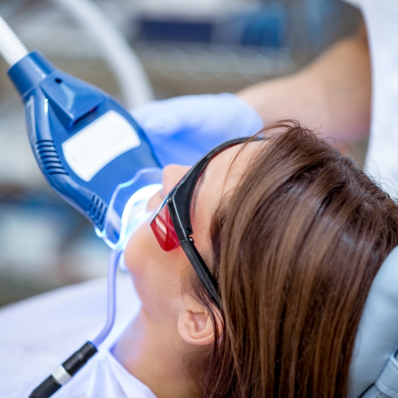 Woman in the dental chair having a teeth whitening light applied to her teeth