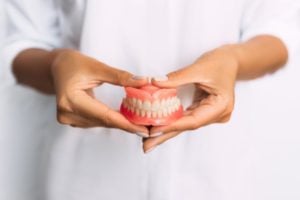 hands holding complete dentures 