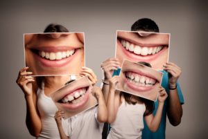 family holding pictures of their smiles 