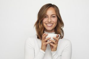 young woman holding mug with temporary veneers on Long Island 