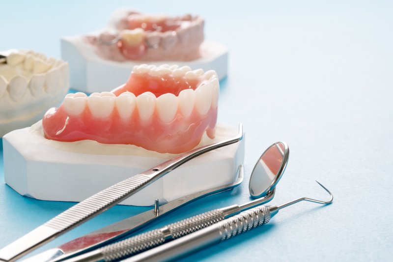 a mouth mold holding a lower denture with dental instruments lying next to it