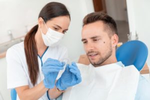 dental assistant looking at Invisalign tray with male patient 