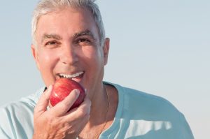 smiling older man eating apple