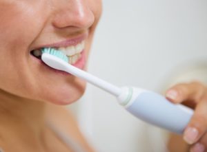 woman brushing with electric toothbrush