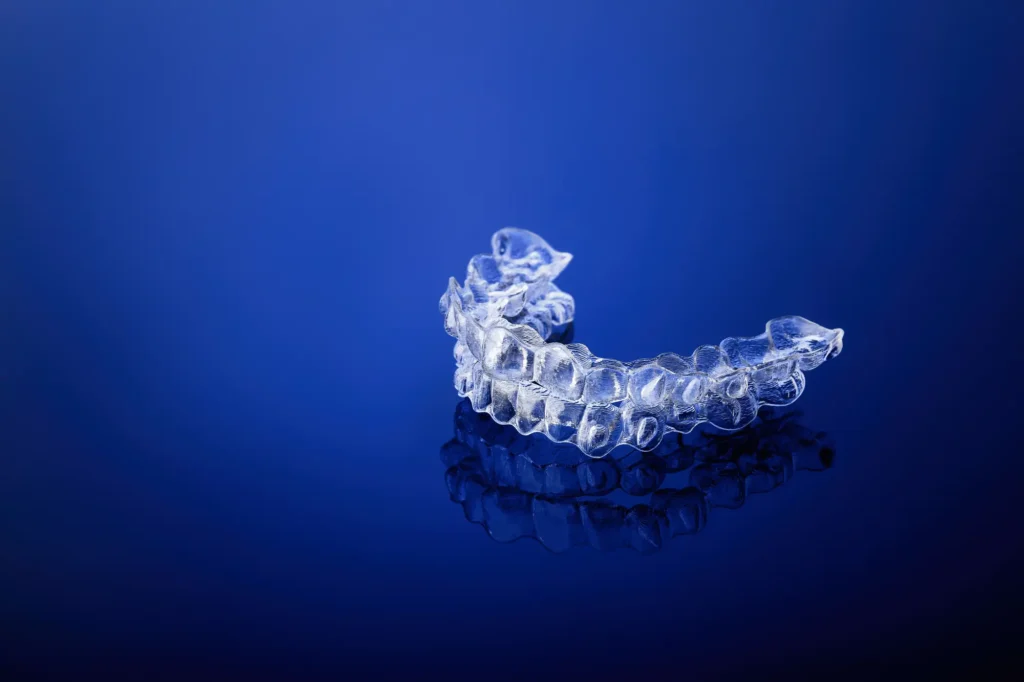 Invisalign Massapequa invisible orthodontic brackets on gradient background